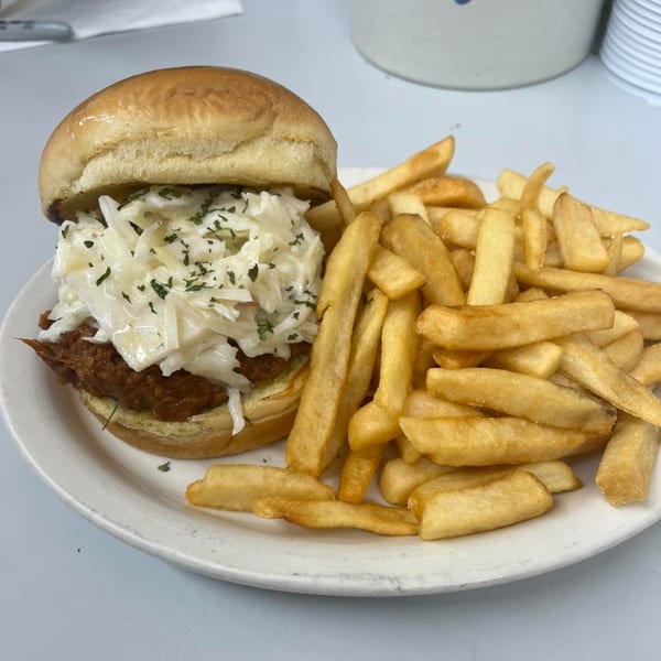 A Pa's Chicken Coupe pulled pork sandwich with coleslaw and a side of french fries.