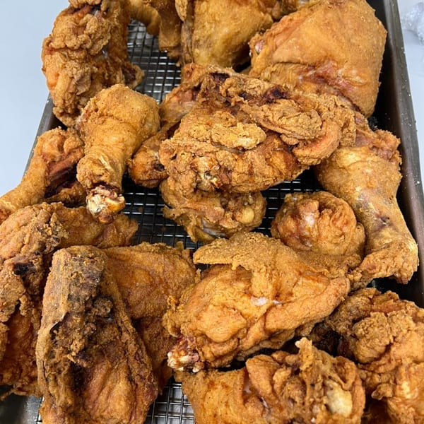 A close-up of a tray filled with golden-brown, crispy fried chicken pieces from Pa's Chicken Coupe.